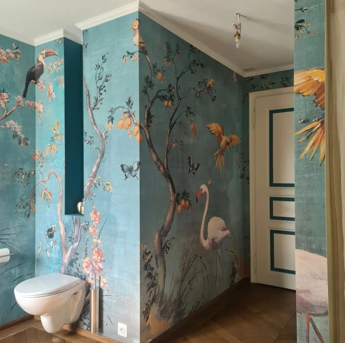Bagno con murale di alberi, fenicotteri e tucani su fondo azzurro
