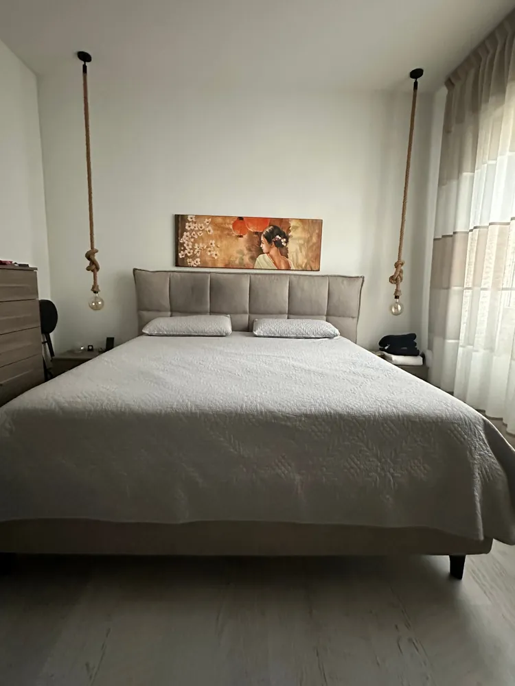 Foto della camera da letto del cliente, con la parete bianca dietro il letto